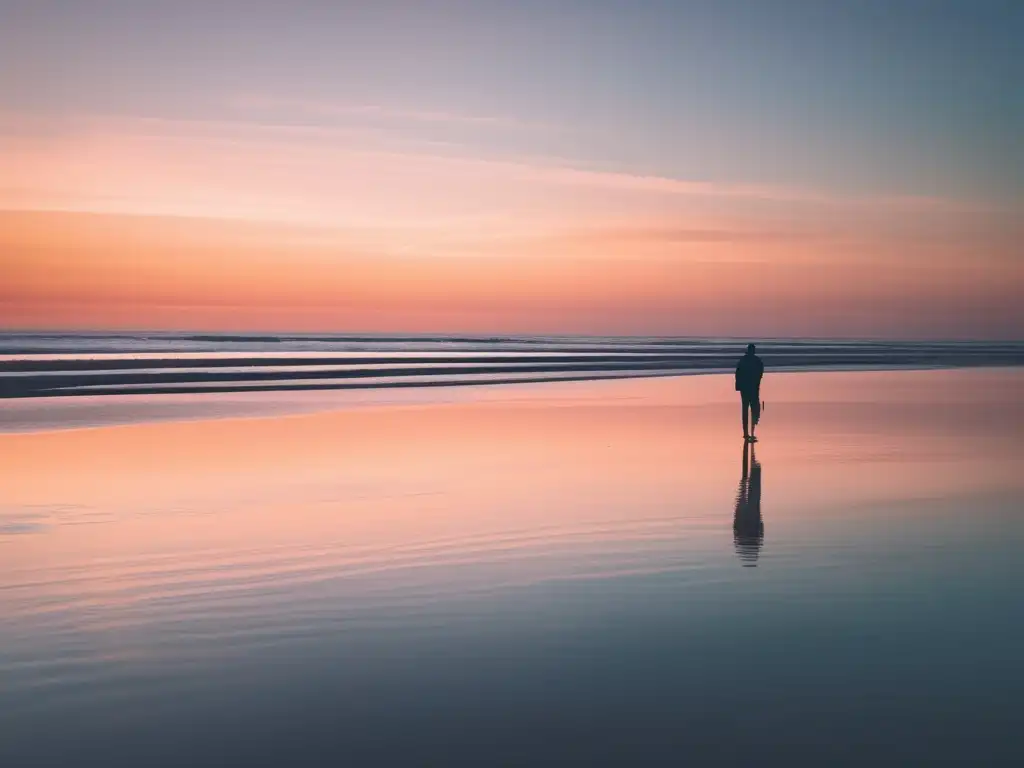 Un tranquilo atardecer en la playa, con una figura solitaria frente al mar